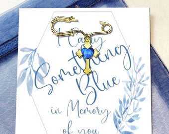 May include: A gold cross charm with a blue heart-shaped crystal, attached to a safety pin. The charm is on a white card with the text "I Carry Something Blue in Memory of You".