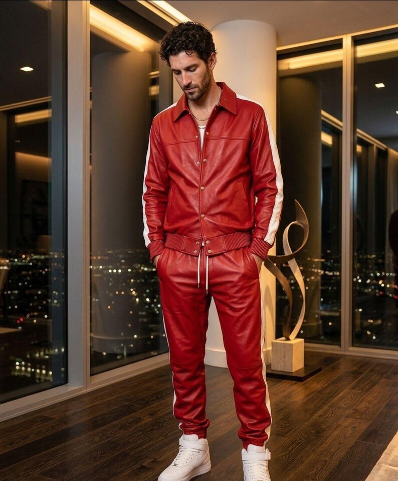 May include: A red leather tracksuit with white stripes on the sleeves and sides of the pants. The jacket has a collared neckline and button closure. The pants have a drawstring waist. The person is wearing white sneakers.