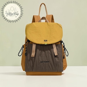 Puede incluir: Una mochila de color mostaza y marrón con el texto "NORTHHANSEN". La mochila tiene un cierre de solapa, correas ajustables y un asa superior. La bolsa tiene cordones negros y un pequeño logotipo en la parte delantera.