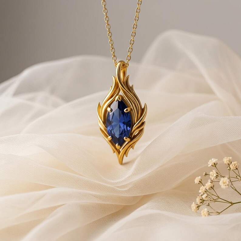 A striking sterling silver Ruby Flow Necklace showcases a brilliant marquise-cut ruby gemstone at its heart. The ruby is securely held by an intricate, organic flame-like silver setting that flows upwards and downwards, creating a dynamic and elegant silhouette. The polished silver reflects light, enhancing the deep red hue of the ruby. This unique flame design pendant is suspended from a delicate silver cable chain, presented against a soft, light background, emphasizing the necklace's