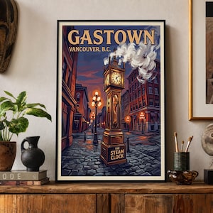 May include: A framed vertical poster depicting the Gastown Steam Clock in Vancouver, B.C. The illustration features a cobblestone street, glowing street lamps, and a clock tower emitting steam against a twilight sky with the text GASTOWN VANCOUVER, B.C.