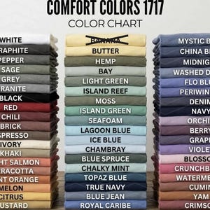 May include: A color chart for Comfort Colors 1717, displaying a variety of folded t-shirts in various colors. The chart includes colors like white, black, red, blue, and green, with the names of the colors printed above each stack of shirts.