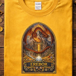 May include: Mustard yellow t-shirt with a detailed graphic of a dragon over a mountain fortress, with the word "EREBOR" below. The design features a dragon, mountains, and treasure. Gildan tag visible.
