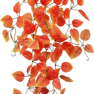 May include: Artificial hanging plant with vibrant orange and yellow leaves. The leaves are heart-shaped and arranged on thin, green stems. The plant is in a black pot, perfect for home decor.