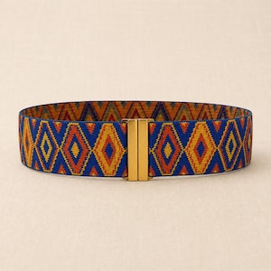 Puede incluir: Cintur&oacute;n ancho y el&aacute;stico con un estampado geom&eacute;trico en azul, naranja y amarillo. El cintur&oacute;n tiene un cierre rectangular dorado. El patr&oacute;n consiste en formas de diamante. Este accesorio se puede usar con vestidos, faldas o pantalones.