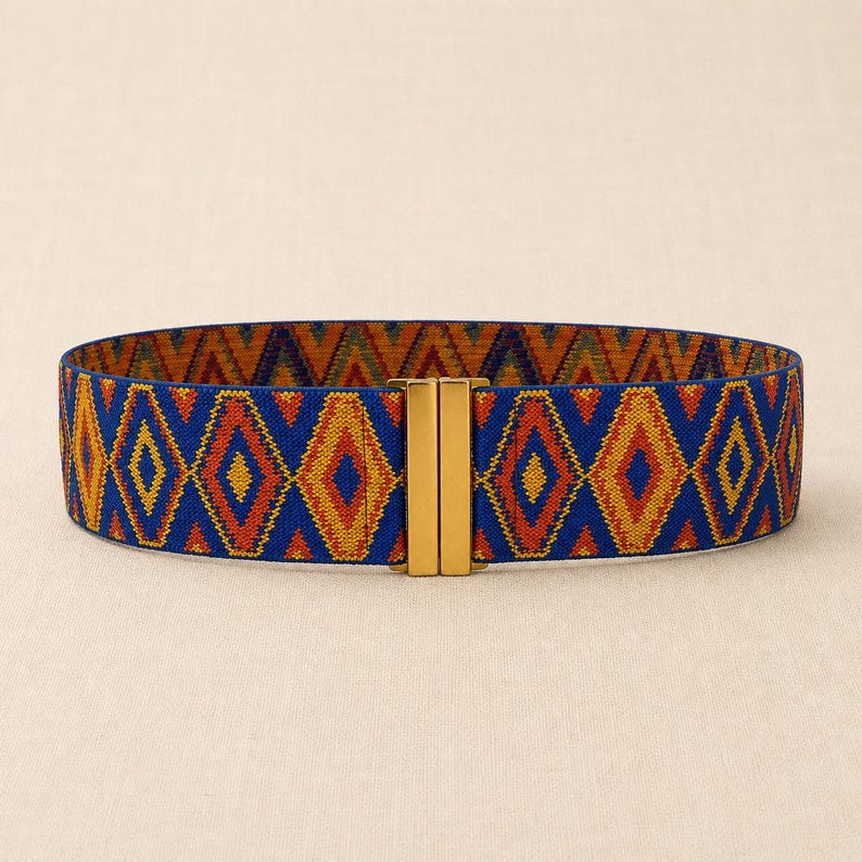 Puede incluir: Cintur&oacute;n ancho y el&aacute;stico con un estampado geom&eacute;trico en azul, naranja y amarillo. El cintur&oacute;n tiene un cierre rectangular dorado. El patr&oacute;n consiste en formas de diamante. Este accesorio se puede usar con vestidos, faldas o pantalones.