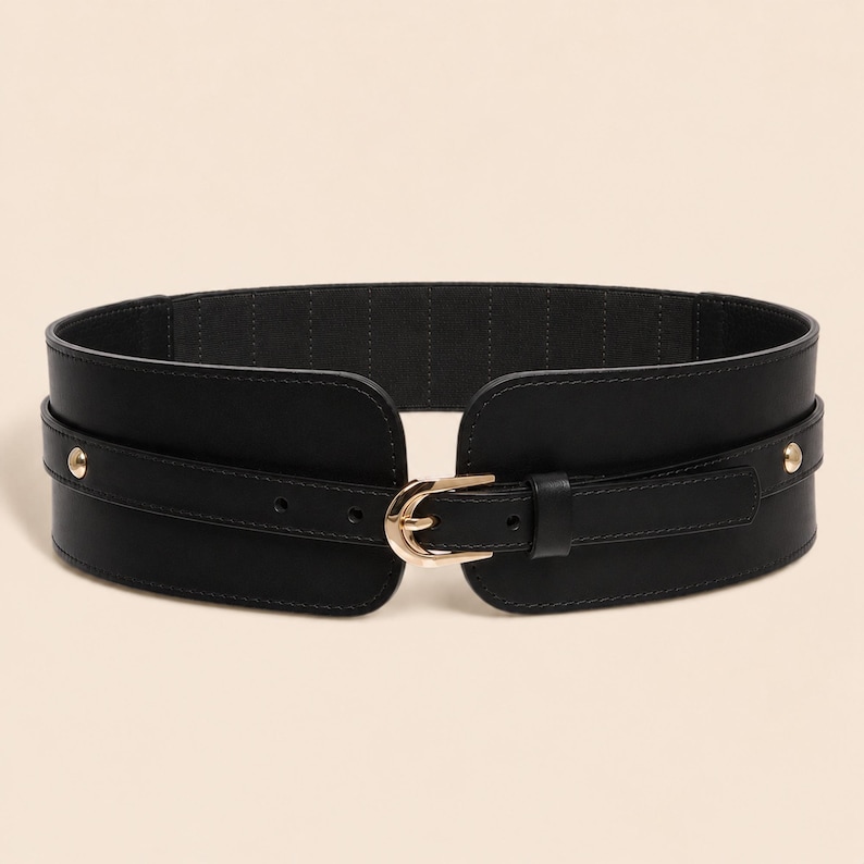 May include: A wide black elasticized waist belt featuring a smooth front panel with a gold-toned metal buckle and matching gold-toned studs on each side. The belt has a structured design with a central strap that secures through the buckle.