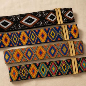 Puede incluir: Cuatro cinturones el&aacute;sticos coloridos con patrones geom&eacute;tricos. Los cinturones presentan dise&ntilde;os de diamantes y flechas en varios colores, incluyendo negro, marr&oacute;n, azul, amarillo y rojo. Cada cintur&oacute;n tiene un cierre met&aacute;lico dorado.