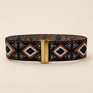 Puede incluir: Cintur&oacute;n ancho negro con un patr&oacute;n geom&eacute;trico en marr&oacute;n, blanco y negro. El cintur&oacute;n presenta un cierre rectangular dorado. El dise&ntilde;o del cintur&oacute;n se repite en el interior. Accesorio de moda.