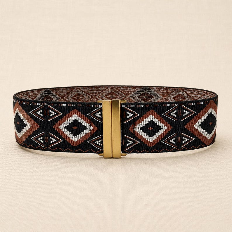 Puede incluir: Cintur&oacute;n ancho negro con un patr&oacute;n geom&eacute;trico en marr&oacute;n, blanco y negro. El cintur&oacute;n presenta un cierre rectangular dorado. El dise&ntilde;o del cintur&oacute;n se repite en el interior. Accesorio de moda.