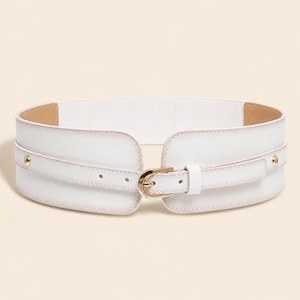 May include: A wide white elastic waist belt featuring a central gold-toned metal buckle and a matching narrow strap overlay. The design includes two small gold-toned metal studs on the sides and a clean, smooth finish across the front surface.