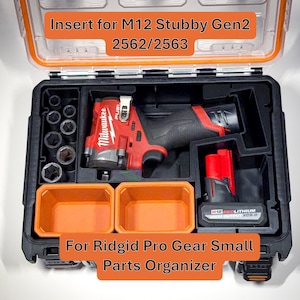 May include: Black and orange tool organizer with the text "Insert for M12 Stubby Gen2 2562/2563" and "For Ridgid Pro Gear Small Parts Organizer." The organizer contains a red and black power tool, sockets, and two orange containers.