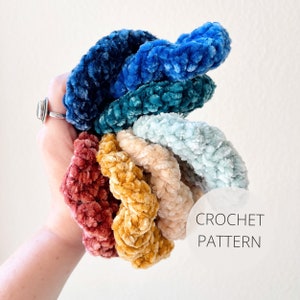 May include: A set of seven crocheted hair scrunchies in various colors, including teal, blue, light blue, beige, yellow, and red. The scrunchies are made with a soft, fuzzy yarn and are stacked on top of each other. The text "CROCHET PATTERN" is visible in the image.