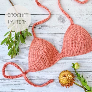 May include: A coral crochet bikini top with adjustable straps. The top is made with a simple stitch pattern and has a triangle shape.