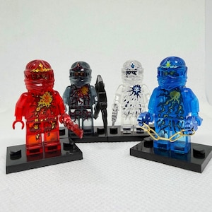 May include: Four colorful action figures on black bases. The figures are transparent red, gray, white, and blue. Each figure has a unique design and accessories, including weapons and chains. The figures are posed in a row.