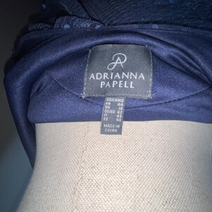 May include: A navy blue formal headpiece with sequin and fabric details. The label reads "ADRIANNA PAPELL" with size information. Made in China.
