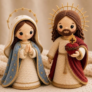 May include: Two crochet dolls representing religious figures. The left doll wears a blue cloak with gold star embroidery and a white head covering. The right doll has brown hair, a beard, and a red cloak, holding a red heart with a cross.
