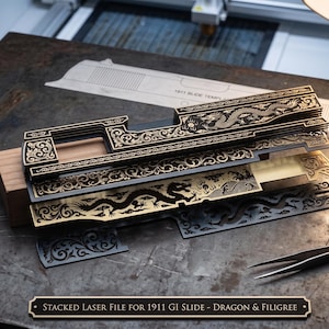 May include: A set of stacked, laser-cut metal plates featuring intricate dragon and filigree engravings. The plates are layered, showcasing detailed patterns in black and gold tones. A small plaque at the bottom reads: STACKED LASER FILE FOR 1911 GI SLIDE - DRAGON & FILIGREE.