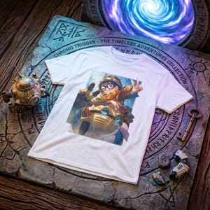 May include: A white t-shirt featuring a graphic print of a character wearing goggles and a scarf, riding a robotic machine. The character is making a peace sign with one hand. The shirt is displayed on a stone-like surface with engraved text.