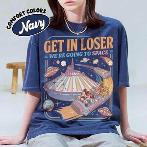 May include: Navy blue t-shirt with the text "GET IN LOSER WE'RE GOING TO SPACE" and a graphic of a space-themed amusement park ride with Mickey and friends. The shirt has a vintage, distressed look.