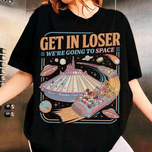 May include: Black t-shirt with a colorful graphic featuring the text "GET IN LOSER WE'RE GOING TO SPACE". The graphic includes a space-themed amusement park ride with cartoon characters, planets, and UFOs.