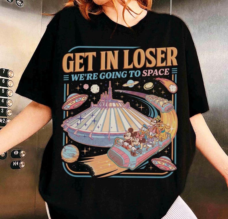 May include: Black t-shirt with a colorful graphic featuring the text "GET IN LOSER WE'RE GOING TO SPACE". The graphic includes a space-themed amusement park ride with cartoon characters, planets, and UFOs.
