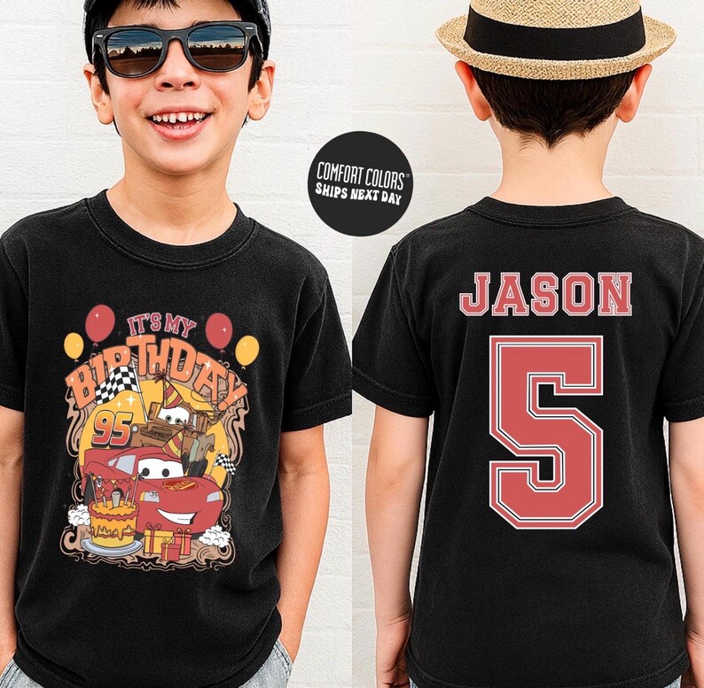 May include: Black t-shirt featuring a colorful birthday design with the text "IT'S MY BIRTHDAY" and a race car graphic. The back of the shirt displays the name "JASON" and the number "5" in red.