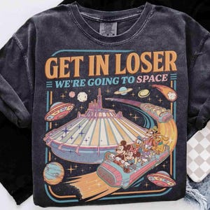 May include: Dark gray t-shirt with a retro graphic that reads "GET IN LOSER WE'RE GOING TO SPACE." The design features a space-themed amusement park ride with cartoon characters and flying saucers.