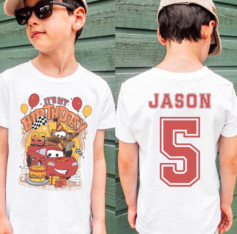 May include: White t-shirt with a colorful graphic featuring a red race car, birthday cake, and the text "It's My Birthday". The back of the shirt displays the name "Jason" and the number "5" in red.