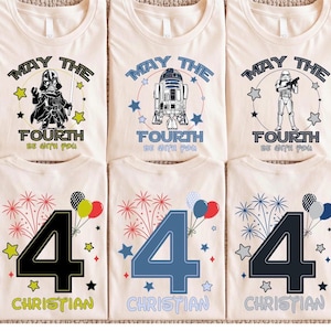May include: Cream-coloured t-shirts featuring Star Wars characters like Darth Vader, R2-D2, and a Stormtrooper, with the phrase "May the Fourth Be With You." Other shirts display the number "4" with fireworks and the name "Christian."