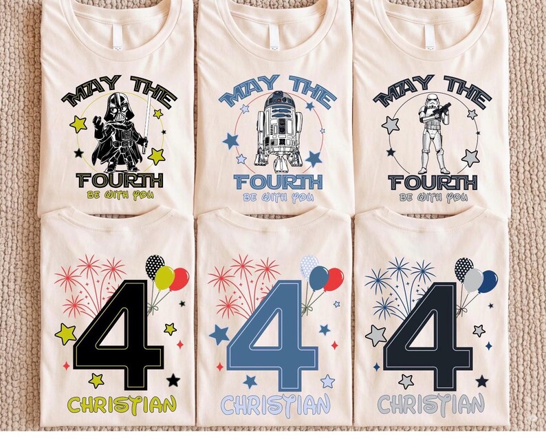 May include: Cream-coloured t-shirts featuring Star Wars characters like Darth Vader, R2-D2, and a Stormtrooper, with the phrase "May the Fourth Be With You." Other shirts display the number "4" with fireworks and the name "Christian."