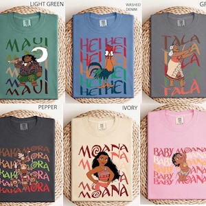 May include: Six different t-shirts in various colors, each featuring a cartoon character and text. Colors include light green, blue, grey, dark grey, ivory, and pink. The shirts have round necks and short sleeves. The text and graphics are in a colorful, cartoon style.