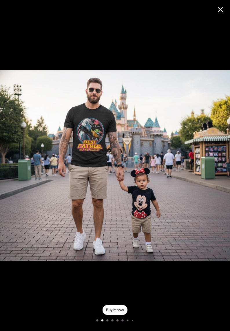 May include: A father and child are walking on a brick path. The father wears a black t-shirt with a "Best Father Ever" graphic and khaki shorts. The child wears a Mickey Mouse t-shirt, shorts, and a Minnie Mouse bow. A castle is in the background.
