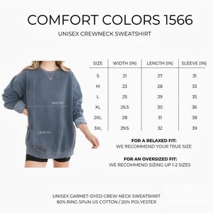 May include: A blue unisex crewneck sweatshirt with the text "COMFORT COLORS 1566". The image includes a size chart with measurements in inches for width, length, and sleeve length. The sweatshirt is 80% cotton and 20% polyester.
