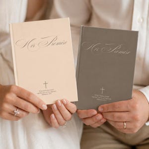 Puede incluir: Se muestran dos libros de tapa dura, uno crema y otro gris. El libro crema tiene el título "Her Promise" en una elegante escritura sobre una cruz y texto. El libro gris tiene el mismo diseño. Los libros son sostenidos por dos personas.