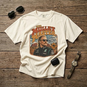 Könnte beinhalten: Cremefarbenes T-Shirt mit einem Retro-Grafikdesign eines Mannes mit Sonnenbrille und dem Text "The Mullet Master Valtteri Bottas". Das Design beinhaltet ein Känguru-Schild und eine Wüstenlandschaft. Sonnenbrille, Uhr und Ohrhörer sind ebenfalls sichtbar.