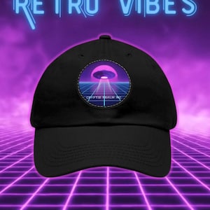 Pode incluir: Boné de beisebol preto com um patch circular com um design retrô de um OVNI sobre uma grade. O texto "CRYPTID REALM INC" está abaixo do OVNI. As palavras "RETRO VIBES" estão acima do boné em azul neon.