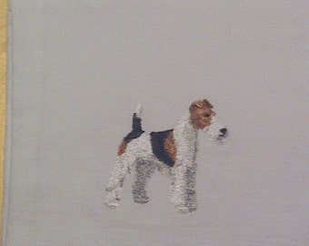 May include: A grey tea towel with an embroidered image of a white and brown wirehaired fox terrier.