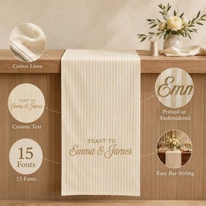 Puede incluir: Un camino de mesa a rayas color crema y beige hecho de tela de algod&oacute;n y lino. El centro presenta el texto "TOAST TO Emma & James" en una fuente cursiva. Los recuadros circulares muestran la textura, opciones de texto, 15 fuentes, bordado y estilo.