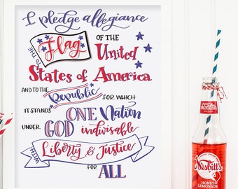 May include: A framed print with the Pledge of Allegiance written in cursive script. The text is in blue and red, with stars and a red, white, and blue flag graphic. The print is on a white background and is framed in white.