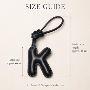 May include: Black leather letter "K" keychain with a knotted strap. The letter measures approximately 6 cm, and the folded strap is approximately 16 cm long. The material is sheepskin leather. The image includes the text "SIZE GUIDE".
