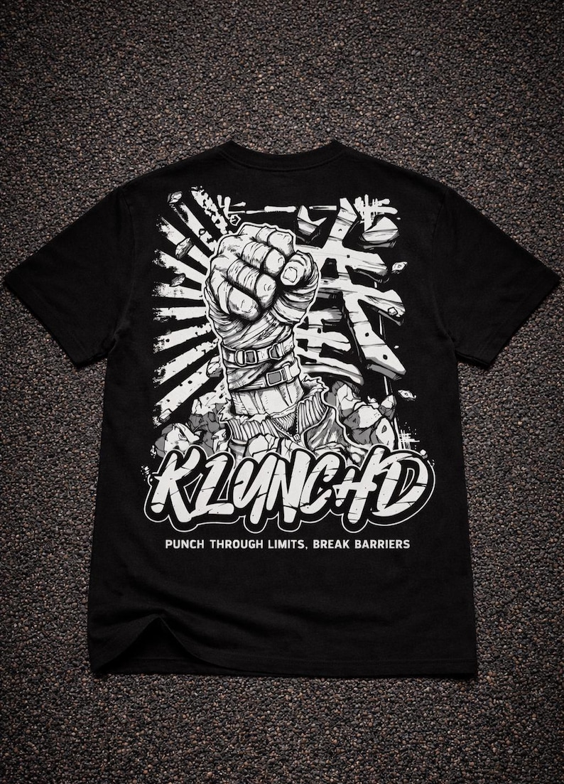 May include: A black t-shirt featuring a white graphic of a wrapped fist punching through a surface. The design includes Japanese characters, the text KLUNCHD, and the phrase PUNCH THROUGH LIMITS, BREAK BARRIERS printed in a bold, white font.