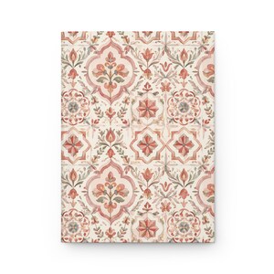 Puede incluir: Un cuaderno rectangular con un patrón repetitivo de motivos florales y geométricos complejos en tonos rojo apagado, rosa suave y verde salvia sobre un fondo color crema. El diseño incluye flores estilizadas y formas de estrellas.