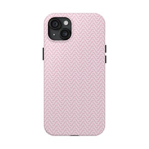 May include: A light pink phone case with a white wavy pattern. The case has a camera cutout and black side buttons. The design is a repeating wave pattern, creating a textured look. The case is designed to fit a smartphone.