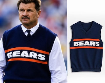 May include: A navy blue V-neck sweater vest featuring a horizontal orange stripe across the chest with the word BEARS printed in white block letters. The knit garment has a ribbed neckline, armholes, and hem, providing a classic sleeveless look.