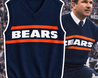 May include: A navy blue V-neck sweater vest featuring a horizontal orange stripe across the chest with the word BEARS printed in white block letters. The sleeveless knit garment has ribbed trim at the neckline, armholes, and the bottom hem.