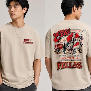 May include: Beige t-shirt with a graphic on the front and back. The front features the text "Ella Fellas" in red and white. The back has a cowboy-themed design with the text "Choosin' Texas, I can tell." and "Ella Fellas Club".