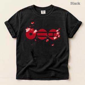 May include: Black t-shirt with a red graphic design. The design features the word "600" in a stylized font, with cherry blossom accents. The shirt is made of a soft material and has rolled-up sleeves.