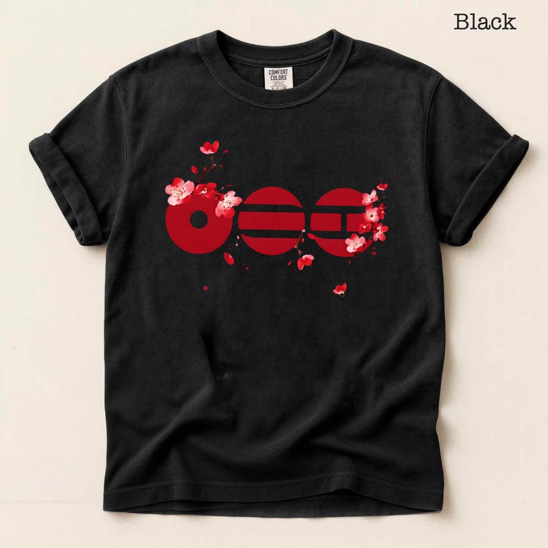 May include: Black t-shirt with a red graphic design. The design features the word "600" in a stylized font, with cherry blossom accents. The shirt is made of a soft material and has rolled-up sleeves.