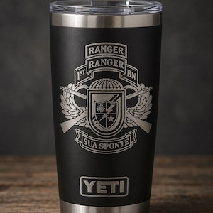 May include: A matte black stainless steel tumbler with a clear lid and a silver laser-engraved 1st Ranger Battalion insignia. The design features the text RANGER, 1ST BN, and SUA SPONTE, along with a shield, wings, and rifles. The YETI logo is at the base.